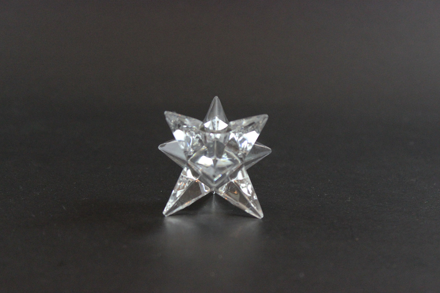 Set of crystal star-shaped candleholders on a dark background
