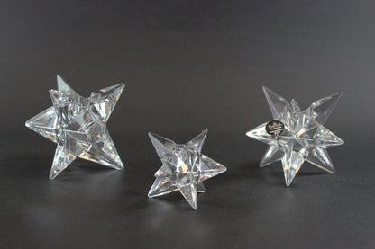 Set of crystal star-shaped candleholders on a dark background