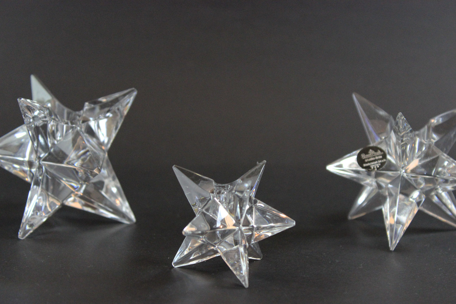 Set of crystal star-shaped candleholders on a dark background