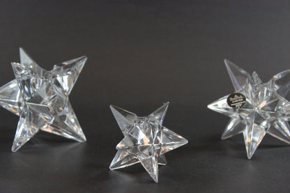 Set of crystal star-shaped candleholders on a dark background