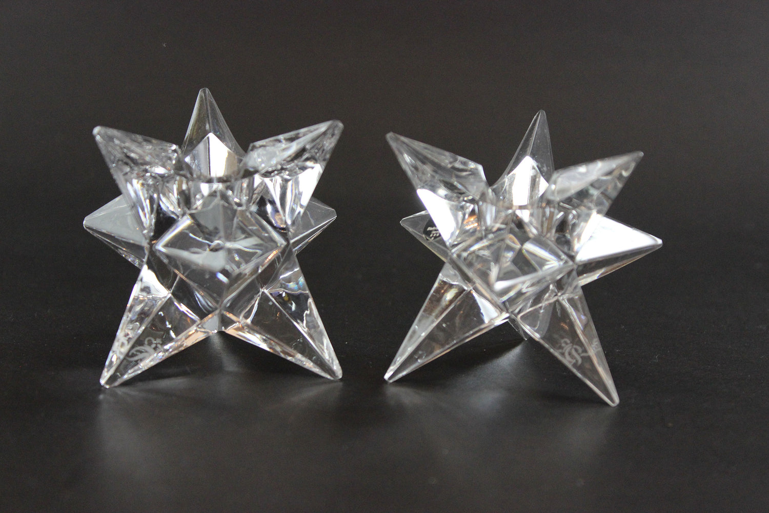 Set of crystal star-shaped candleholders on a dark background