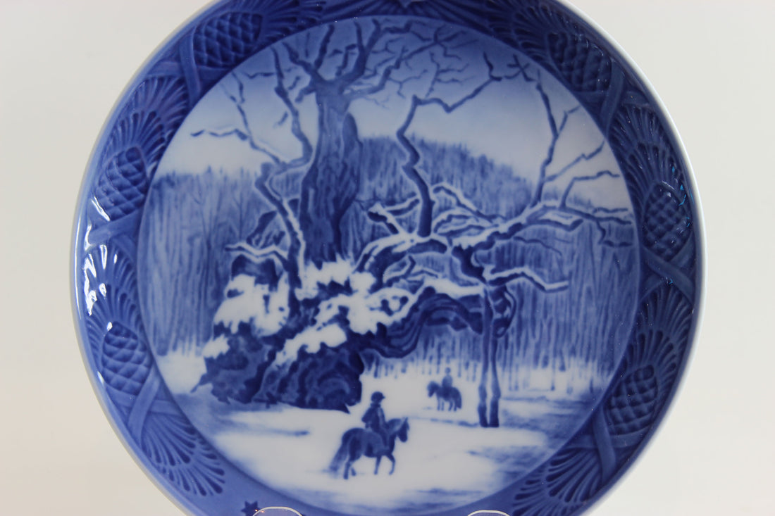 Blue and white ceramic plate with a winter landscape design featuring trees and a horse.