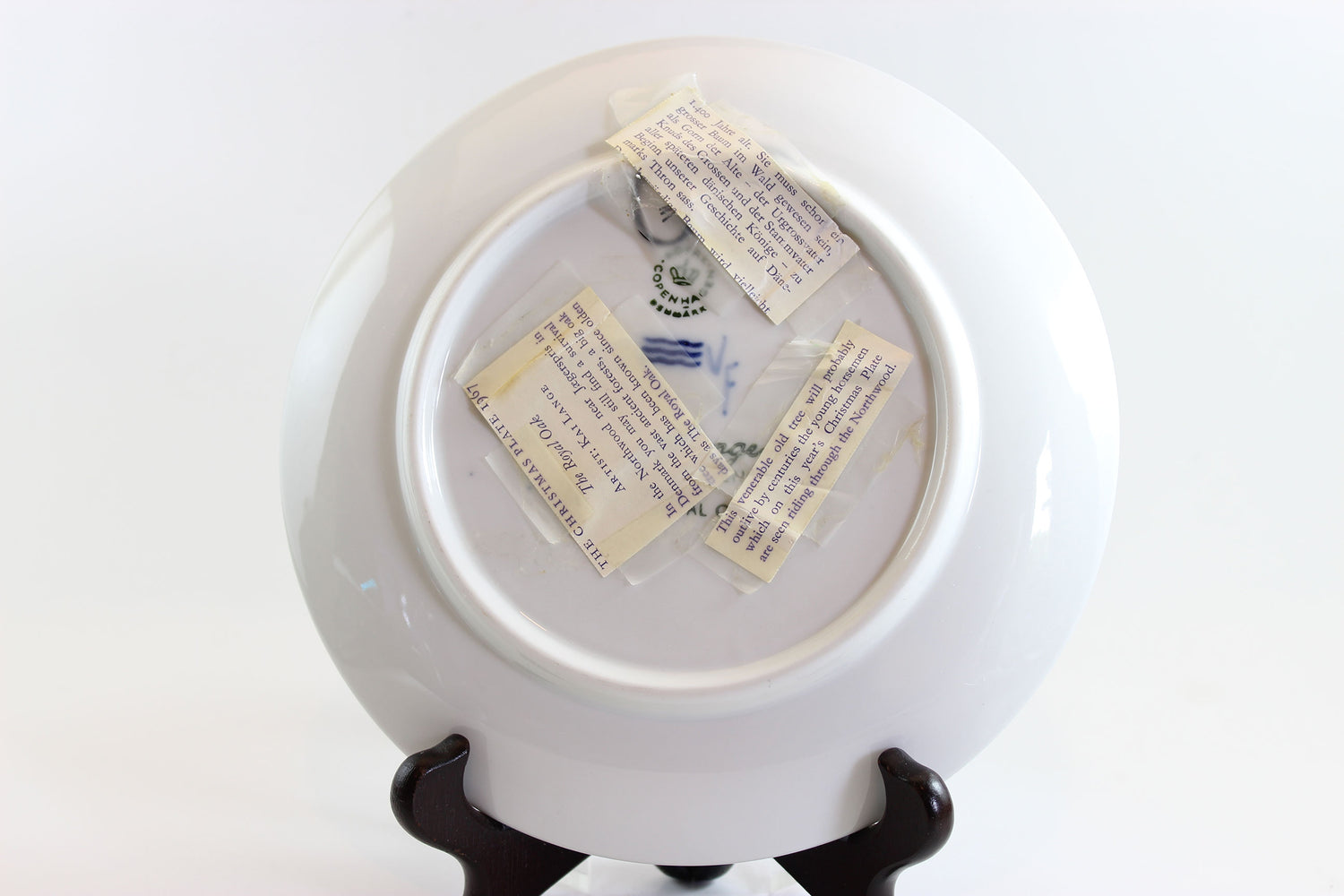 White ceramic plate with text on a stand against a white background