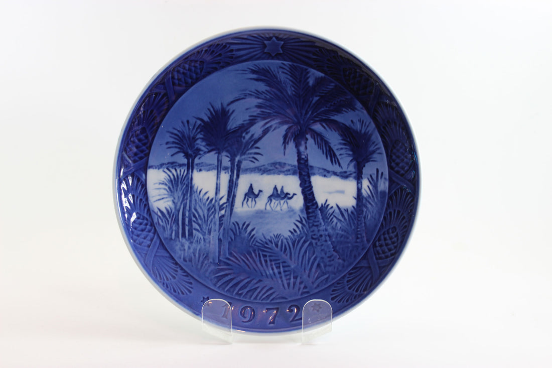 Blue ceramic plate with a scenic design of palm trees and a beach, on a white background.
