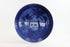 Blue ceramic plate with a scenic design of palm trees and a beach, on a white background.