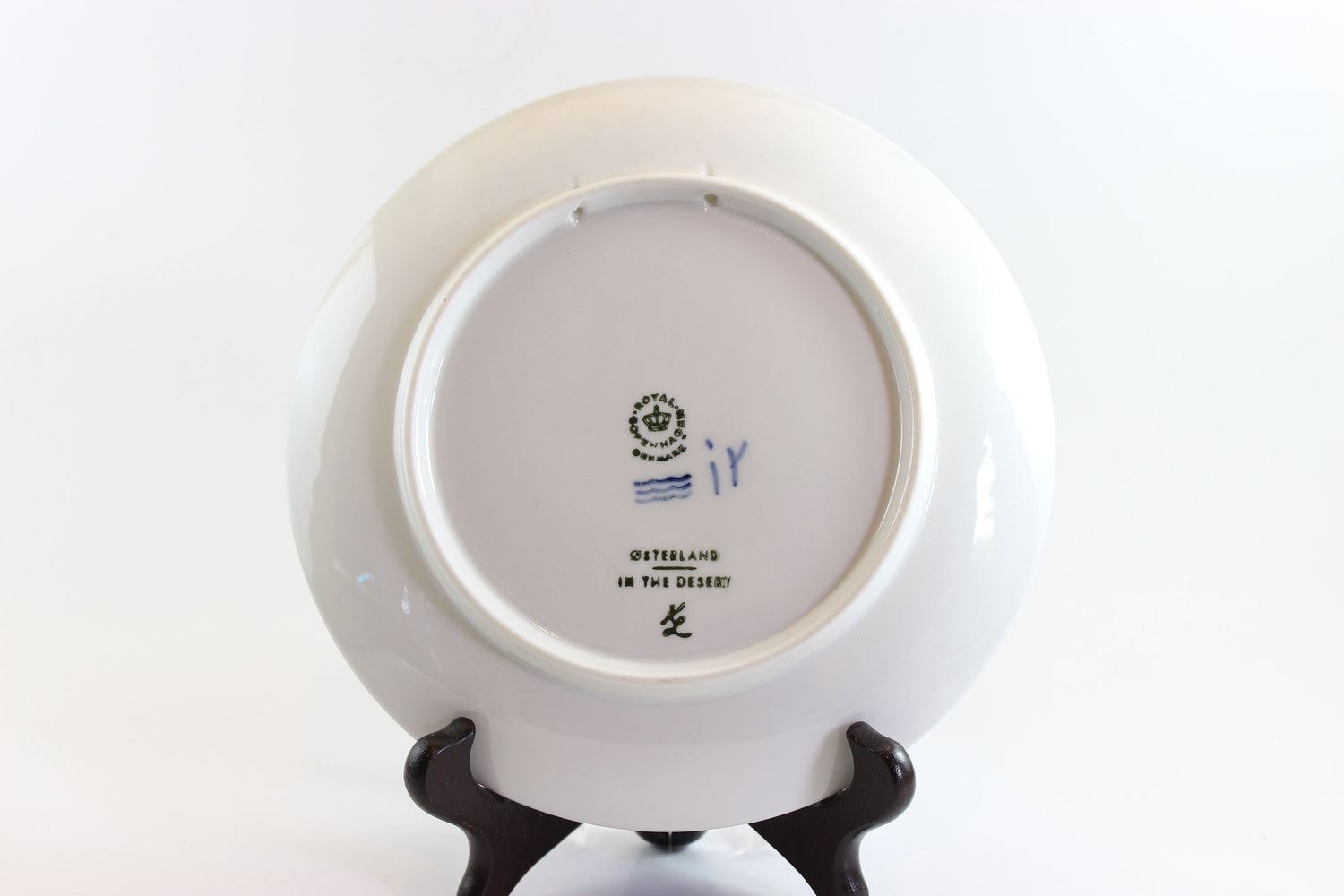 Back view of a white ceramic plate with a stand on a white background