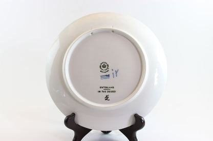 Back view of a white ceramic plate with a stand on a white background