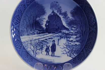 Royal Copenhagen Blue and white ceramic plate with a winter scene of a train and two people, dated 1973.