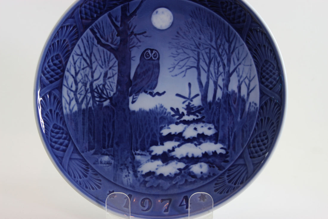 1974 Royal Copenhagen Blue ceramic plate with winter scene and owl, on a white background.
