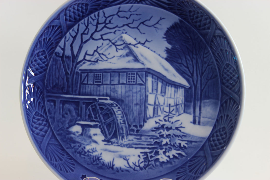 Blue and white ceramic plate with a winter scene of a watermill.