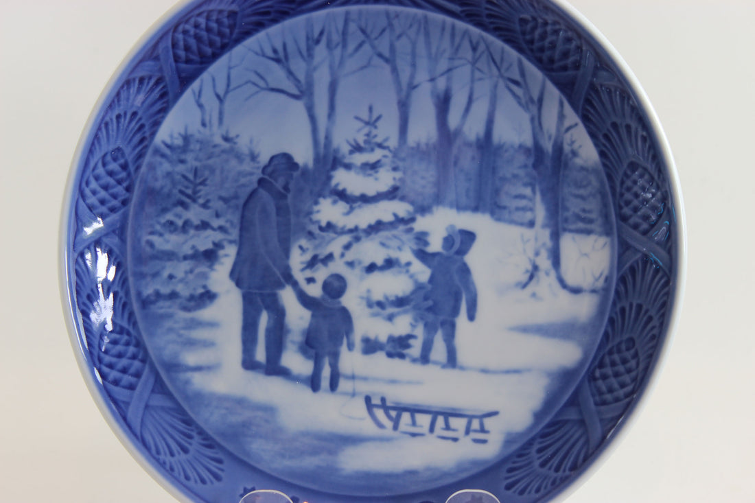 Blue and white ceramic plate with a winter scene of people and a tree.