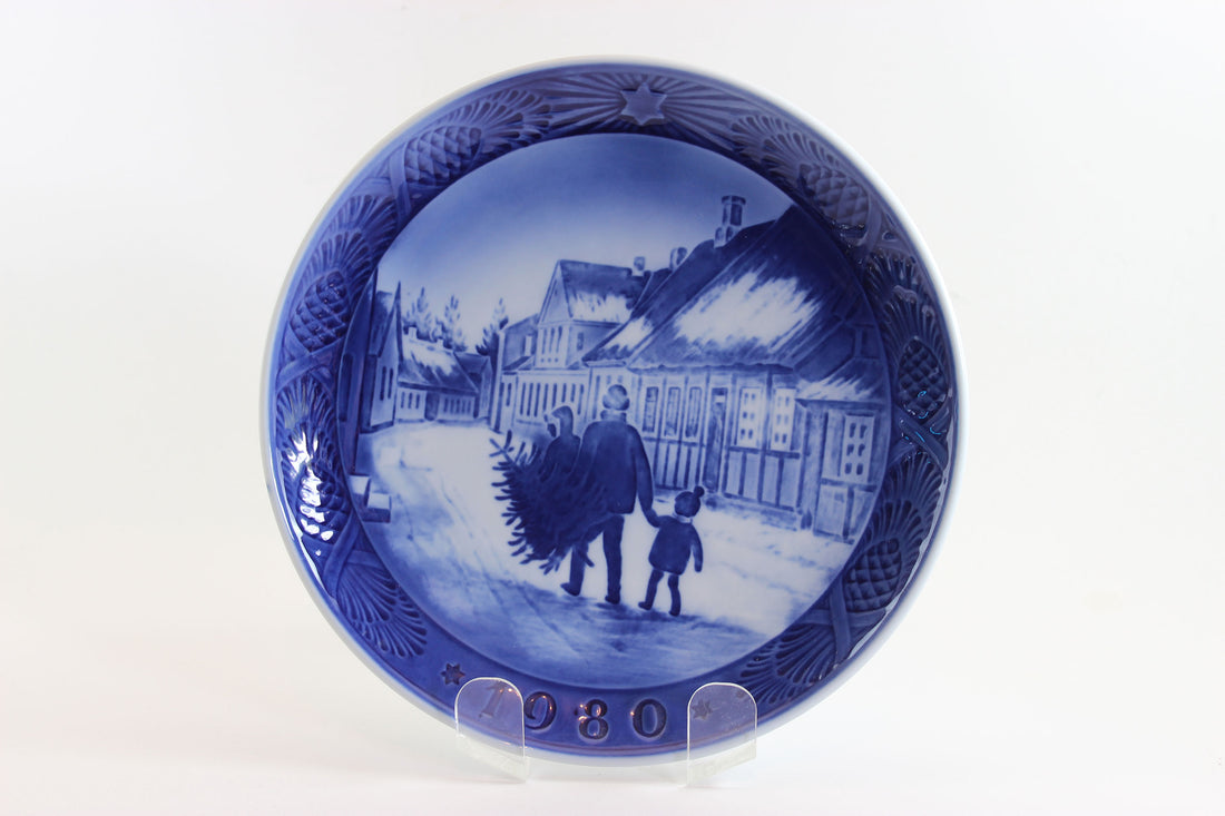 Annual blue and white Christmas plate 1980 with a scene of a man and child walking, on a white background.