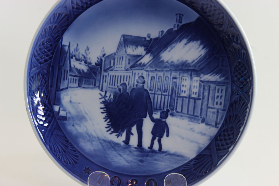 Annual blue and white Christmas plate 1980 with a scene of a man and child walking, on a white background.