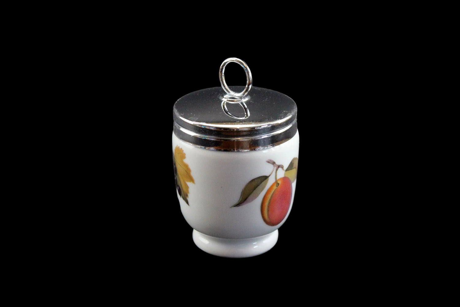 Small ceramic jar with a silver lid on a dark background