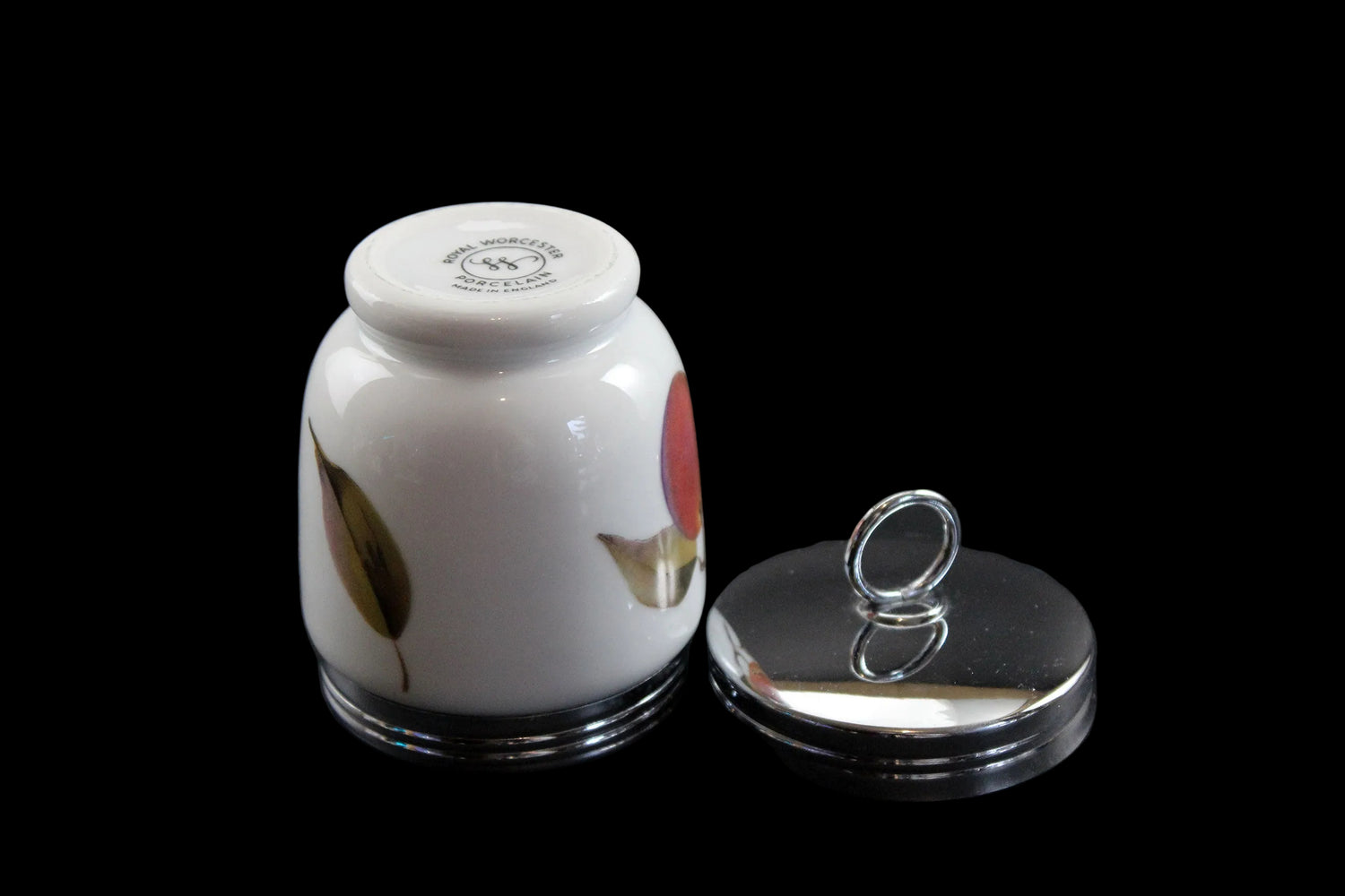 Small white ceramic jar with floral design on a black background