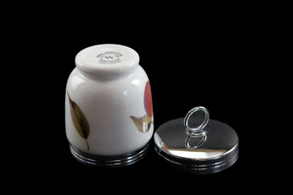 Small white ceramic jar with floral design on a black background