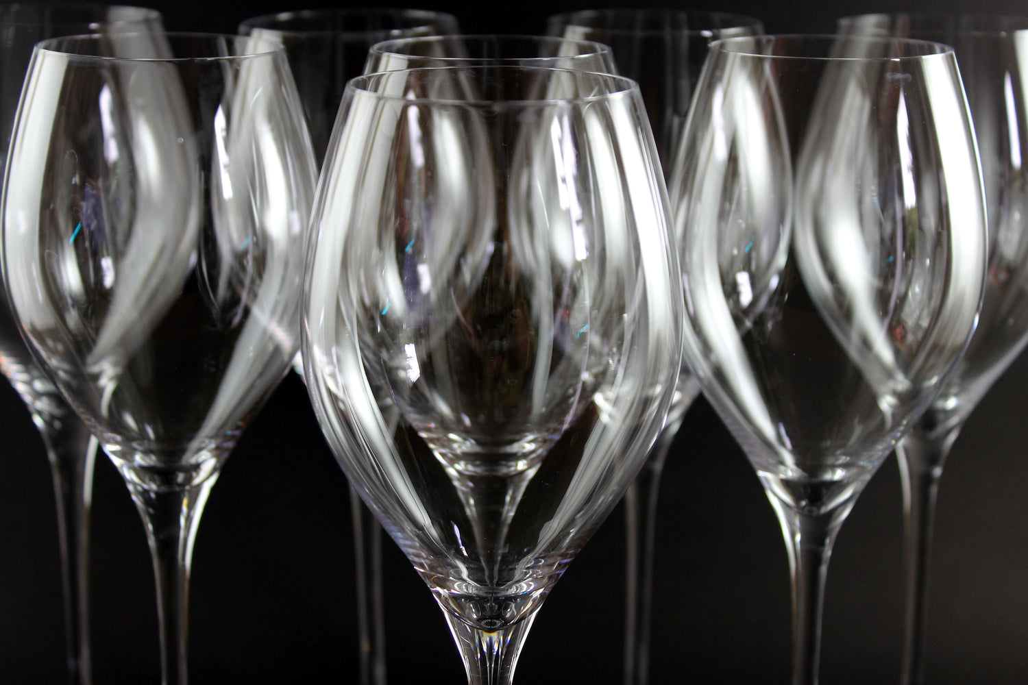 Row of clear wine glasses on a dark background