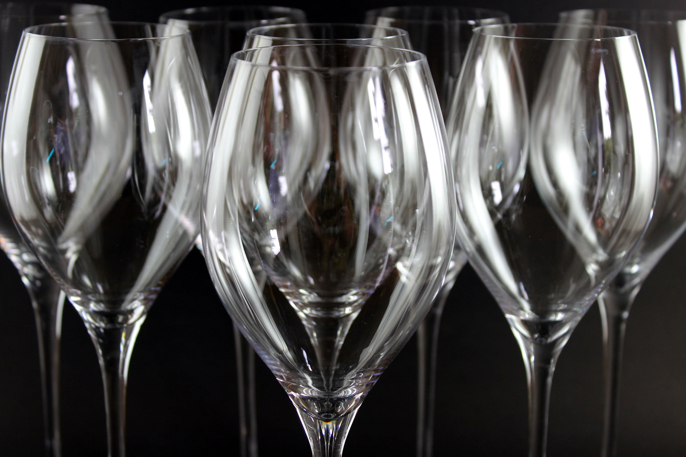 Row of clear wine glasses on a dark background