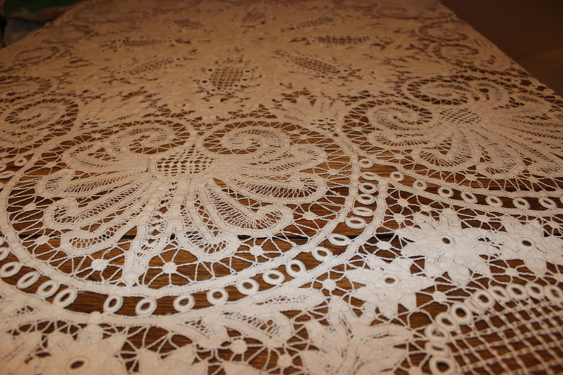 Close-up of a lace tablecloth with intricate patterns on a wooden surface.
