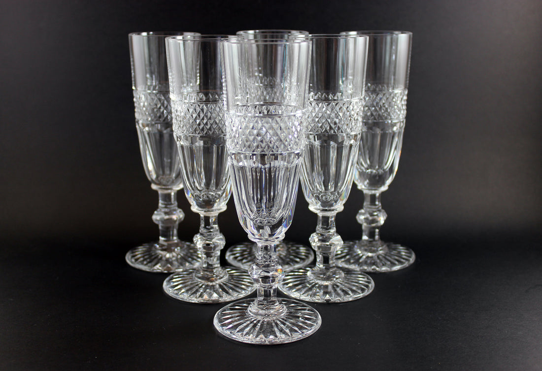 Set of six crystal glasses with diamond cut pattern on a black background