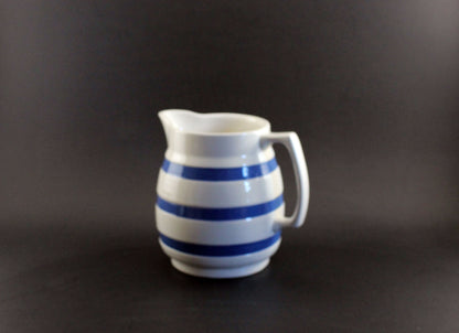 White ceramic pitcher with blue stripes on a dark background