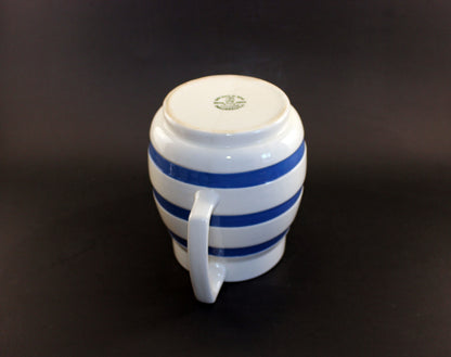 White ceramic pitcher with blue stripes on a dark background