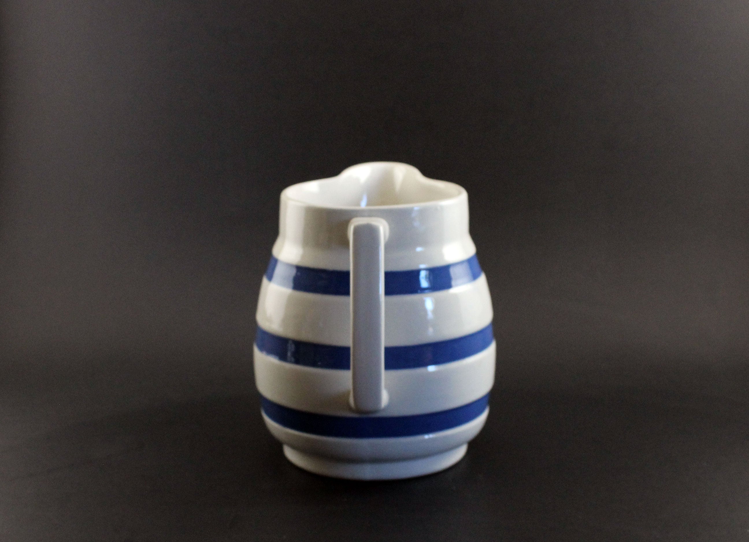 White ceramic pitcher with blue stripes on a dark background