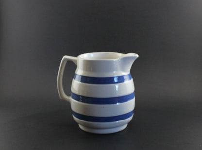 White ceramic pitcher with blue stripes on a dark background