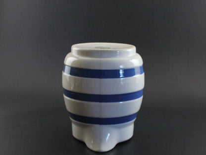 White ceramic pitcher with blue stripes on a dark background