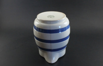 White ceramic pitcher with blue stripes on a dark background