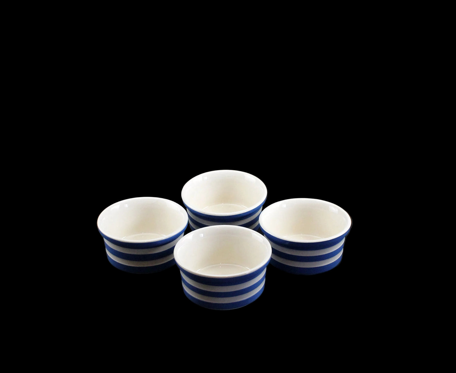 Four ceramic ramekins with blue stripes on a black background