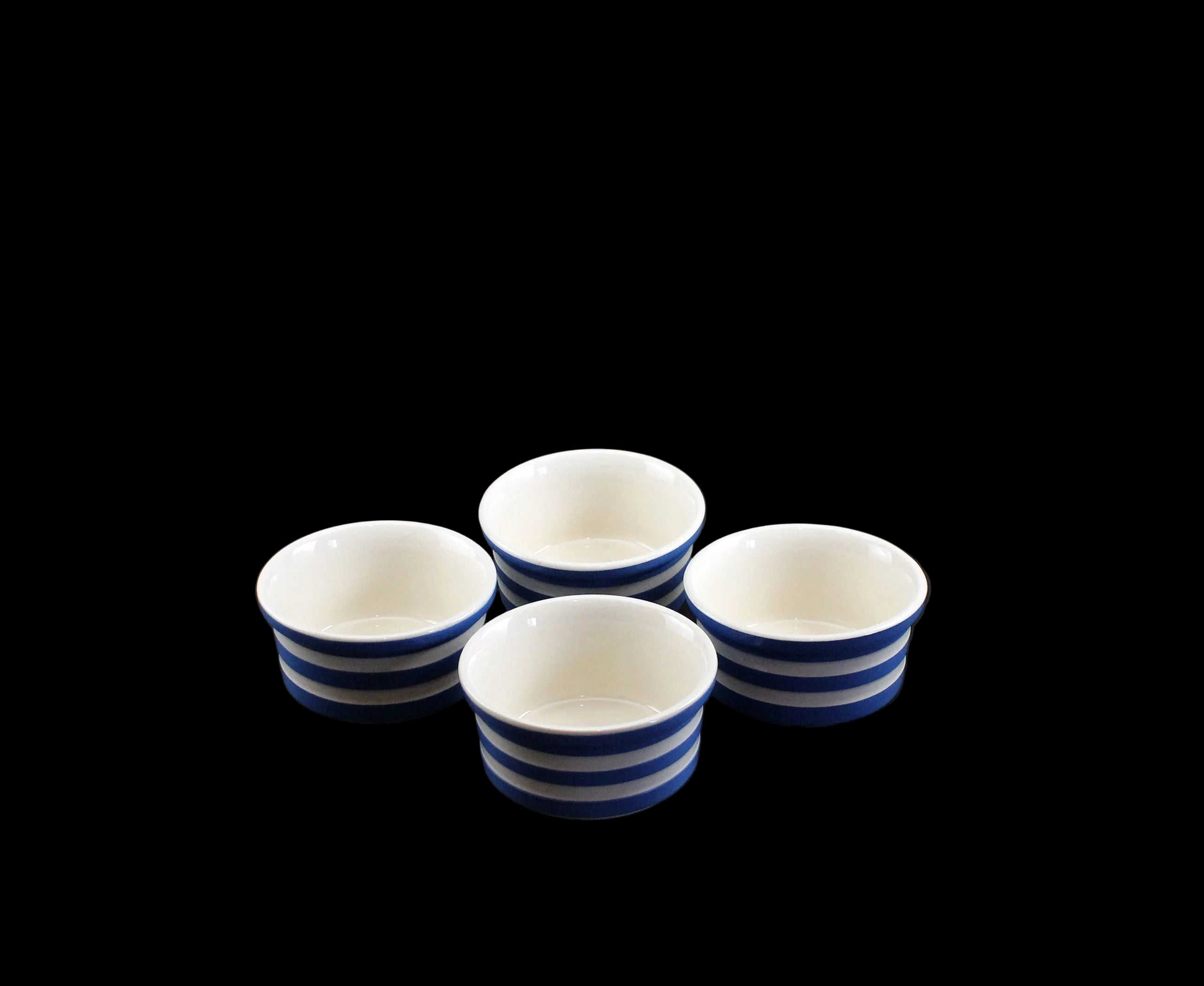 Four ceramic ramekins with blue stripes on a black background