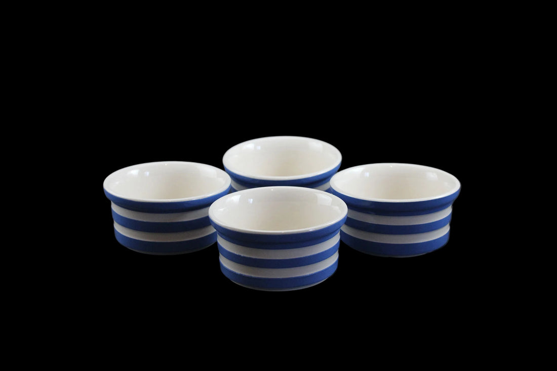 Four ceramic ramekins with blue and white stripes on a dark background