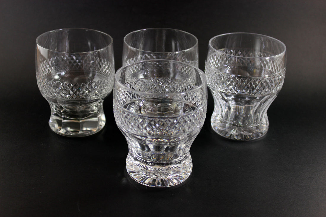 Set of four clear glass tumblers with textured design on a black background