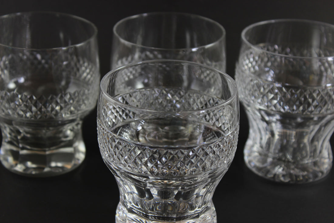 Set of four crystal glasses with intricate patterns on a black background