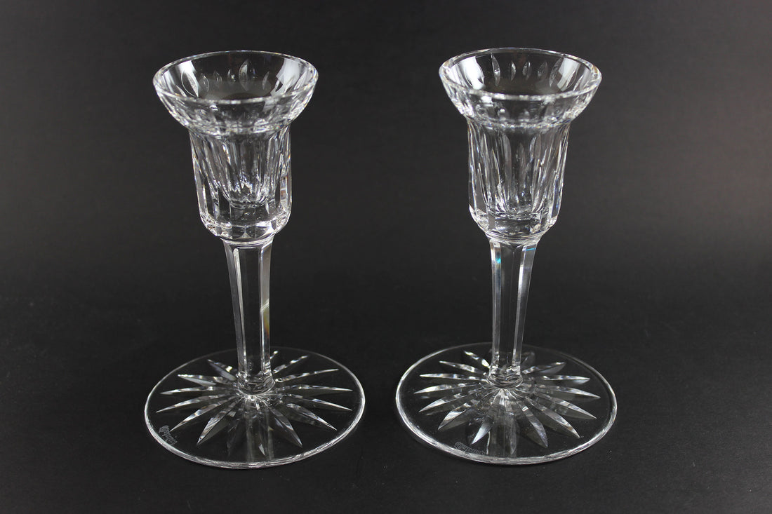 Two clear crystal candle holders on a black background