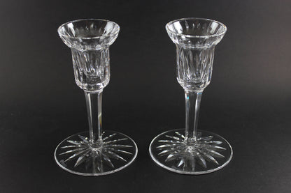 Two clear crystal candle holders on a black background