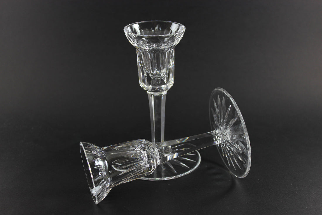 Two clear crystal candle holders on a black background