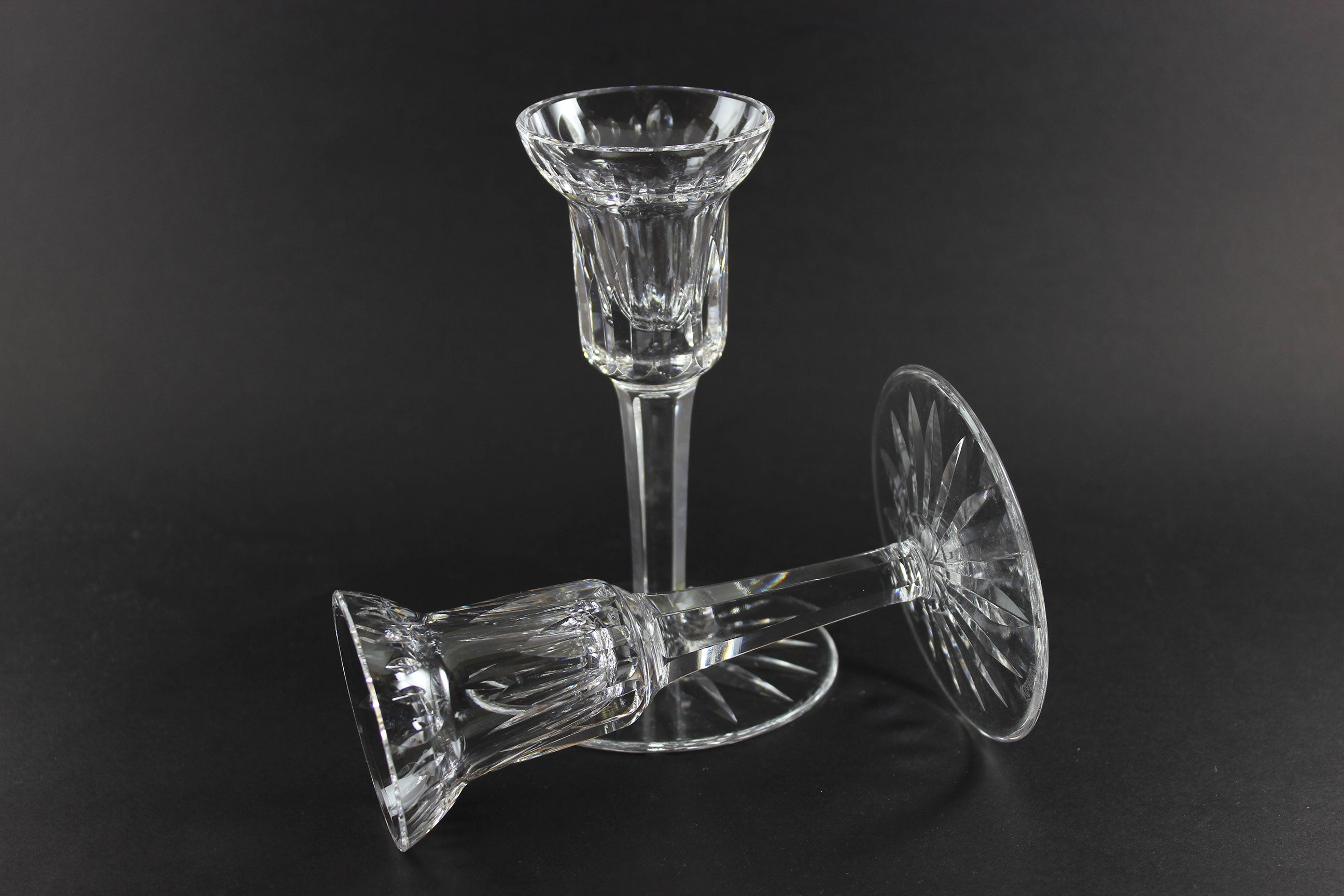 Two clear crystal candle holders on a black background