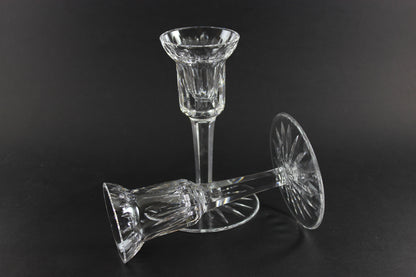 Two clear crystal candle holders on a black background