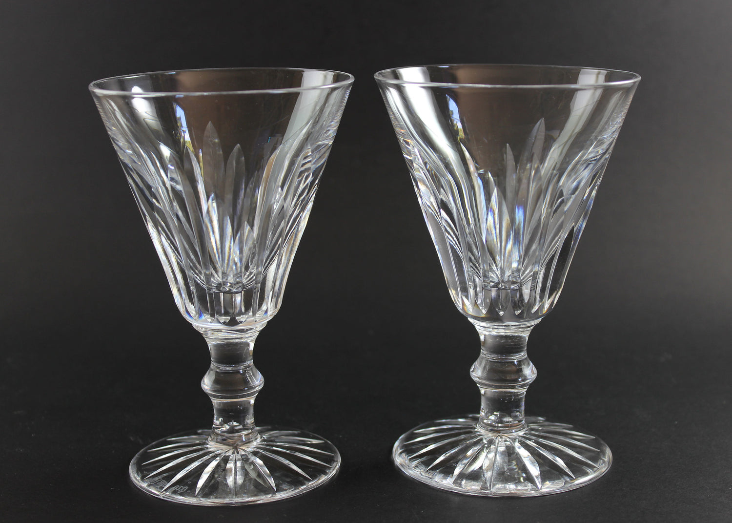 Two crystal glasses with intricate designs on a black background