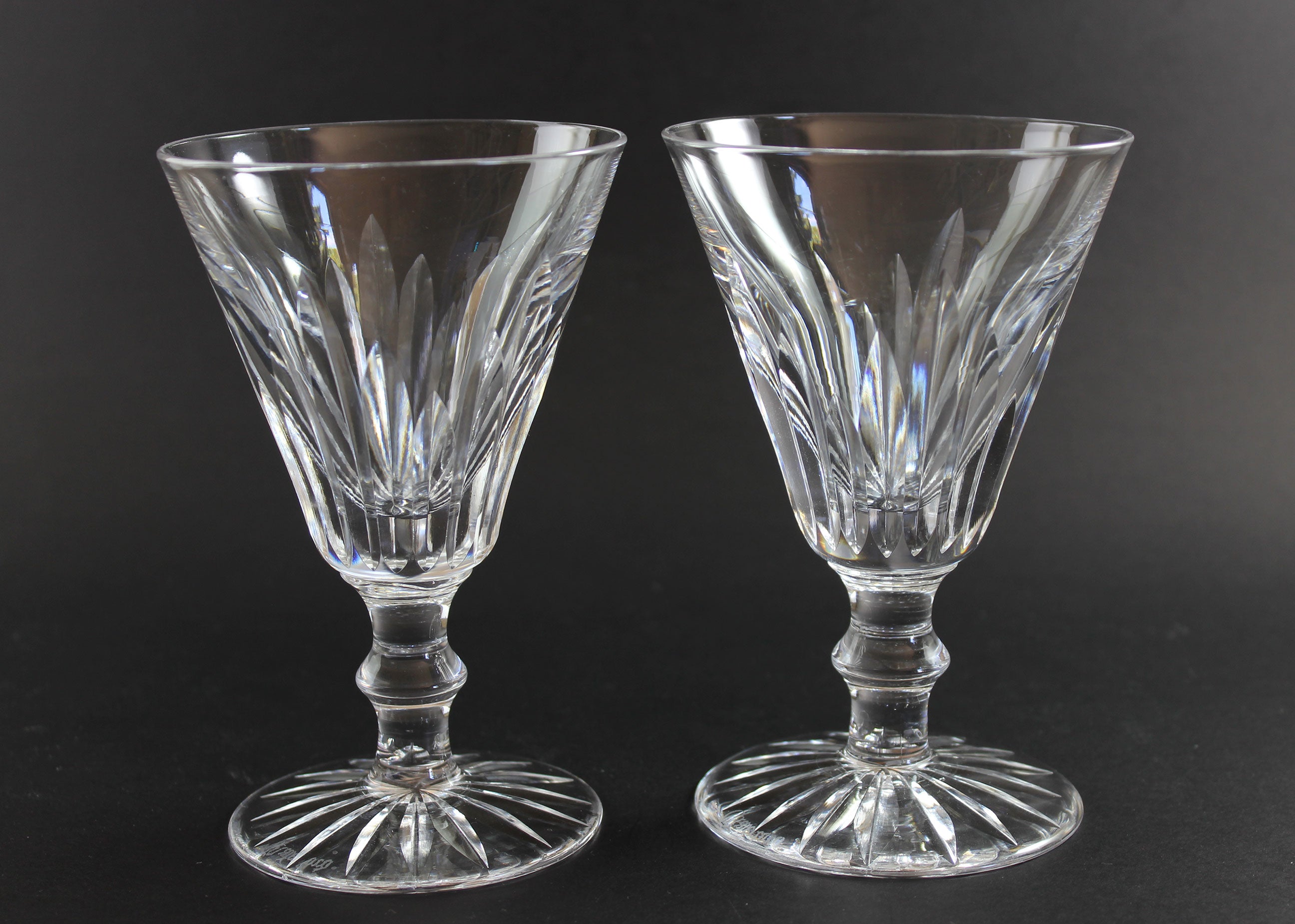 Two crystal glasses with intricate designs on a black background