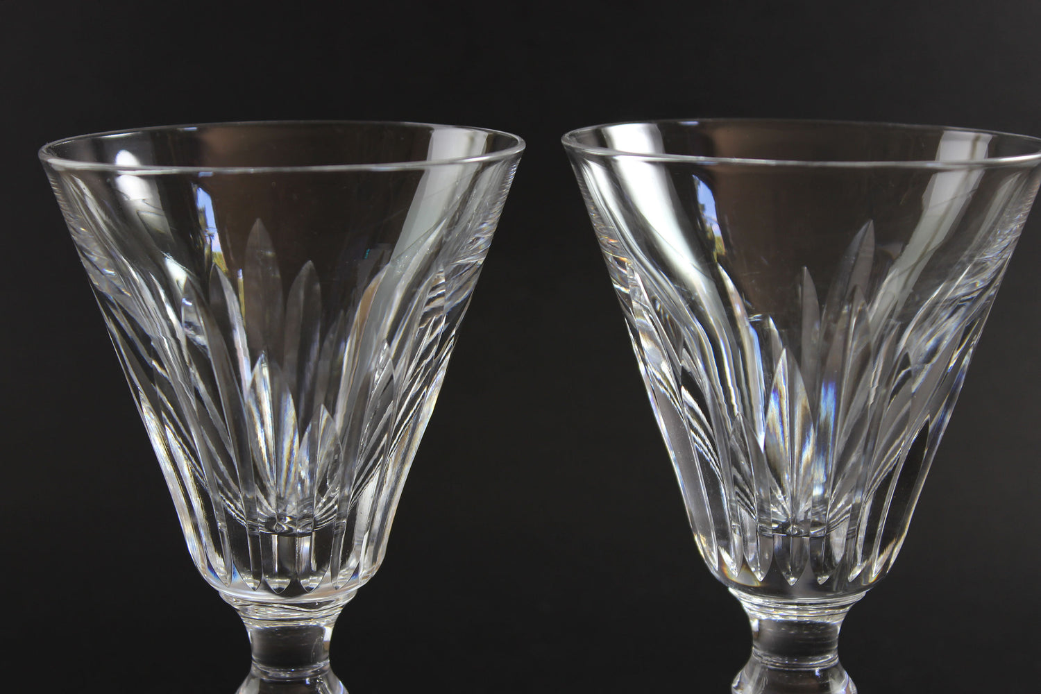 Two crystal glasses with intricate designs on a black background