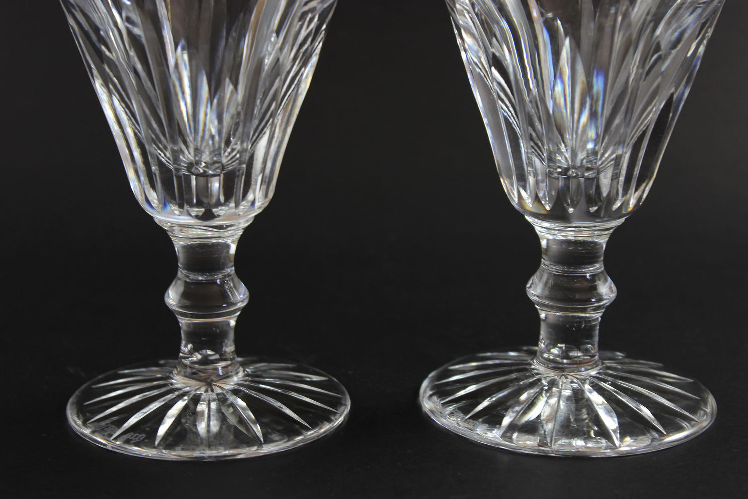 Two cut crystal  goblets with intricate designs on a black background