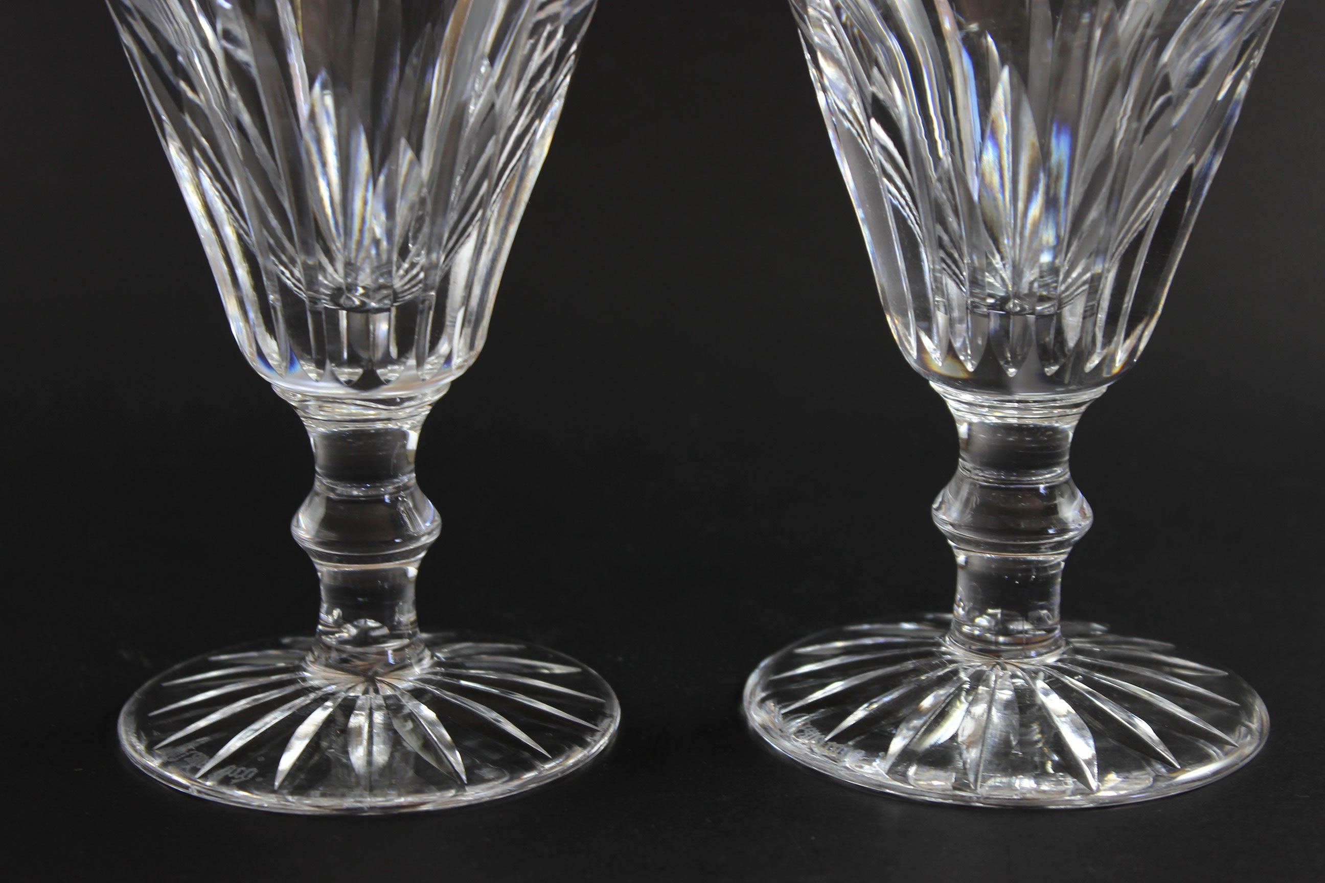 Two cut crystal  goblets with intricate designs on a black background