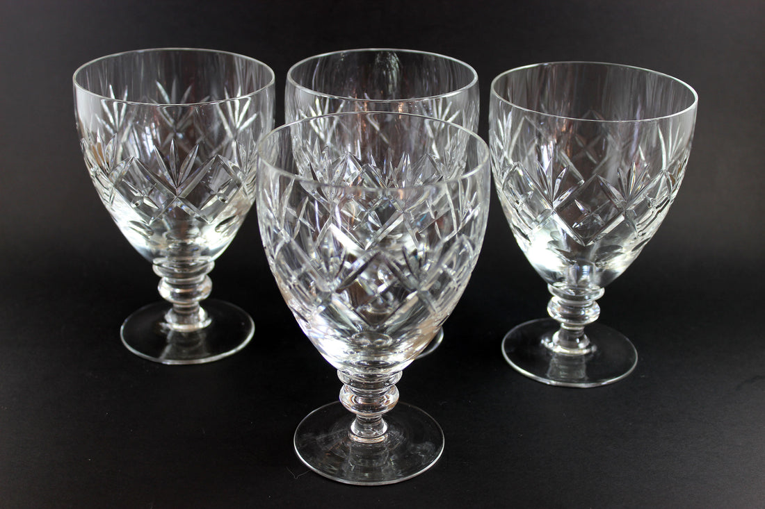 Four crystal glasses with cut patterns on a black background