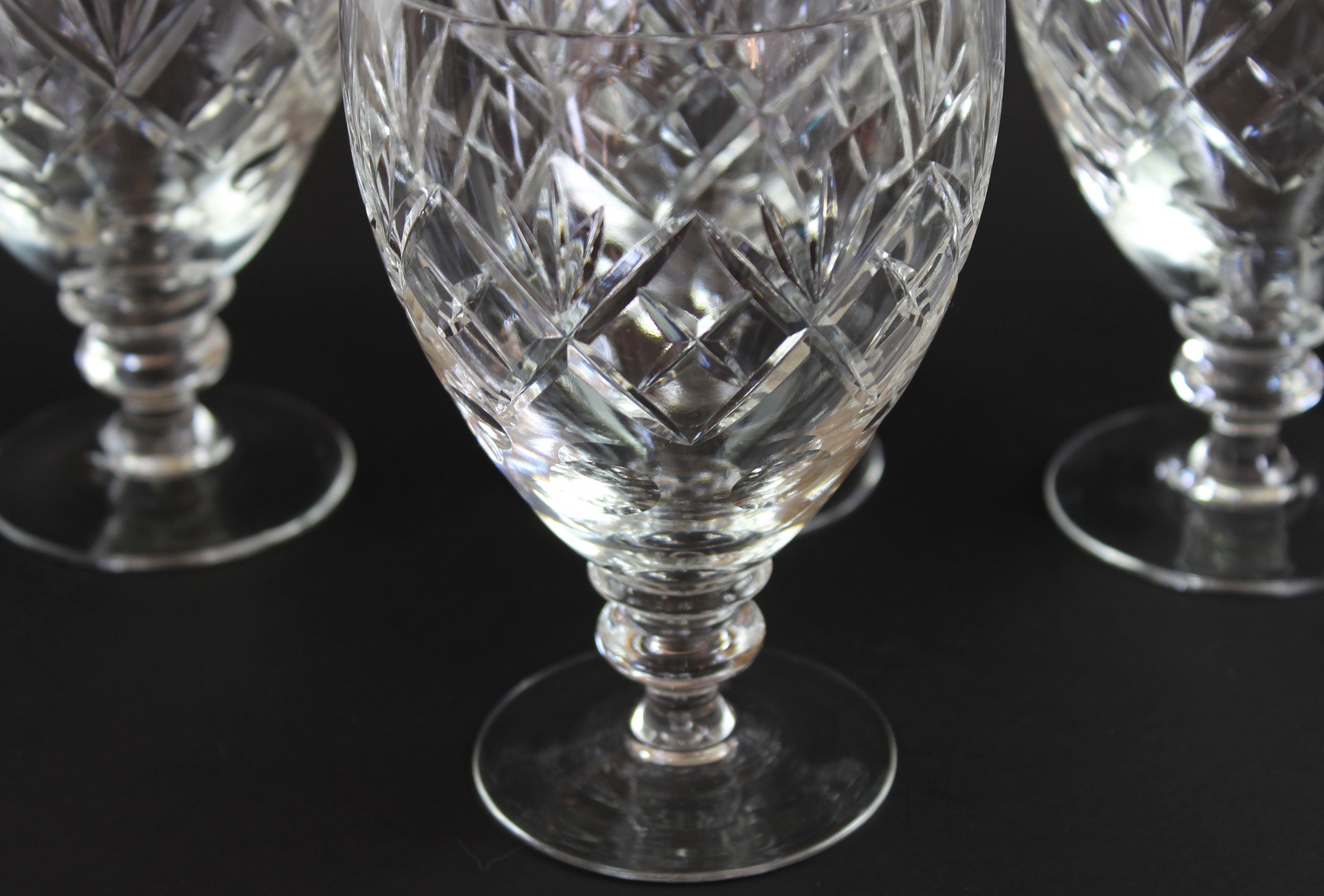 Close-up of crystal glasses with intricate cut patterns on a black background